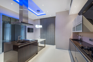 Magnificent kitchen design in light and gray tones with blue ceiling lighting. Dark furniture.