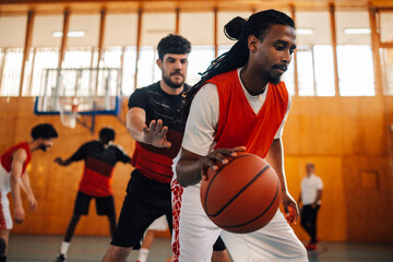 Arabic man dribbling ball while playing basketball with his diverse team