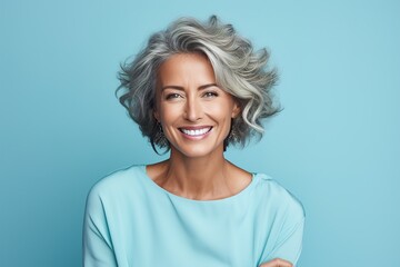 A woman with short gray hair is smiling and wearing a blue shirt