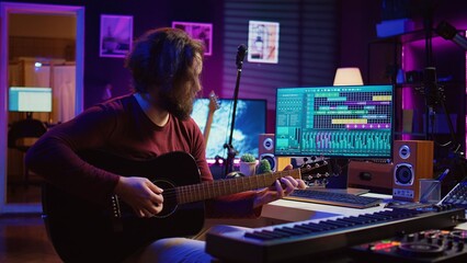 Portrait of male songwriter playing acoustic guitar and recording musical sounds to use for mix and...