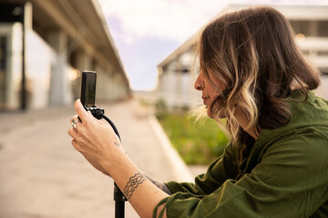 Young woman with piercings and tattoos taking pictures or shooting video with her phone