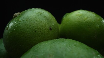 Slices of lime are meticulously arranged in a pile, set against a black background. Each lime slice...