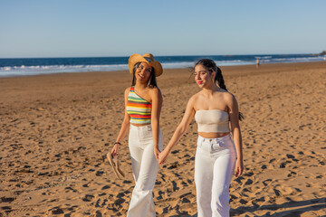 hispanic multicultural Lesbian couple enjoying a romantic beach stroll on a sunny summer day