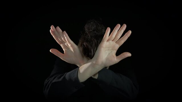 Lady crossing hands no gesture indoor. An unhappy lady crossing her hands to show the stop gesture on the black background.