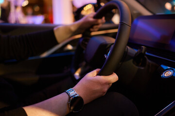 Hand of woman holding steering wheel of car