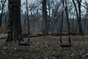 A pair of empty swings in a deserted playground.