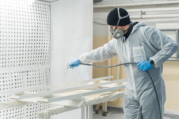 Man in respirator mask painting wooden planks at workshop. High quality photo