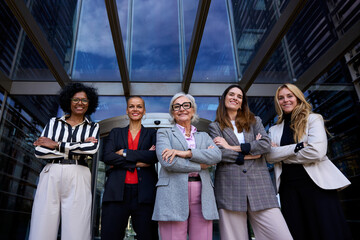 Formal work group of smiling happy diverse business only women standing in a row looking cheerful...