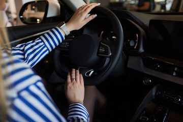 Hand of woman holding steering wheel of car