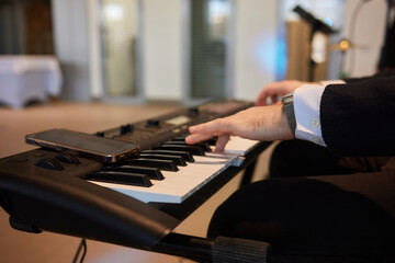 A pianist in a suit plays the keyboard with skilled hands