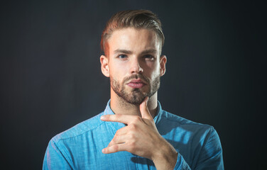 Pensive thoughtful unshaven man in denim shirt with hand on chin making decision feeling doubt....