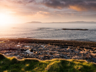 Sunset over ocean with beautiful view on rough stone coastline. Mullaghmore head area, Ireland. Warm color and dramatic cloudy sky. Irish landscape. Popular travel area.