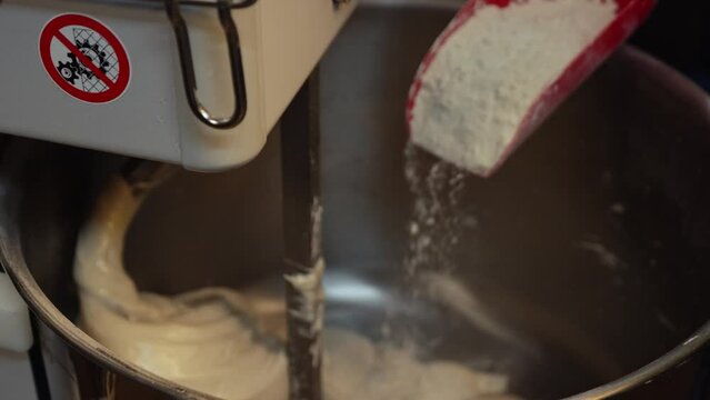 adding flour into the electric mixer machine to knead the dough, kitchen concept. High quality 4k footage