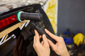 Using a polisher, the person is carefully polishing the cars roof