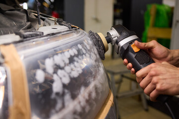 Person using a machine to polish automotive lighting on a car headlight