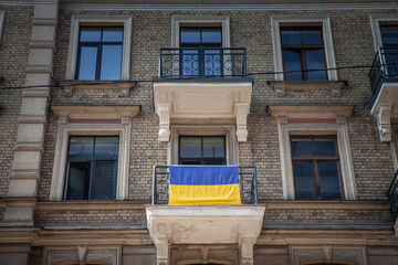 Flags of Ukraine waiving on a balcony in the center of Riga, Latvia, to show solidarity from the Latvians to ukrainians during the war in Ukraine against Russia. - obrazy, fototapety, plakaty