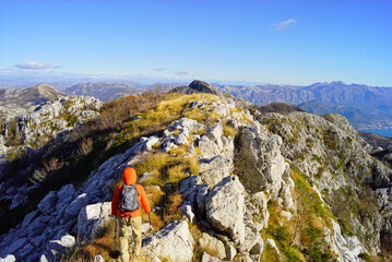 A beautiful mountain landscape with a tourist in a bright jacket photographed from behind. Hiking...