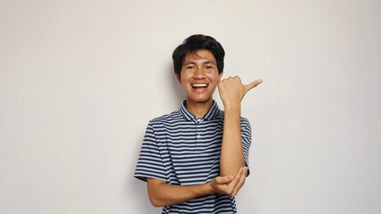 Handsome young Asian man happily pointing to the side