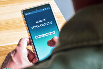 Man using Voice Cloning mobile applications to create AI voice. The danger and benefits of...
