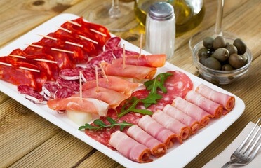 Appetizing cold cuts from Spanish ham, spicy dry-cured sausages and bacon with olives and arugula...