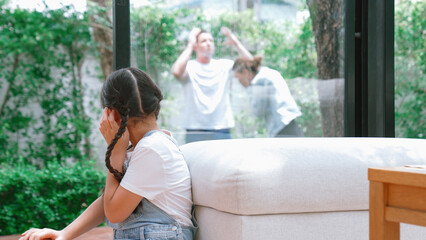 Stressed and unhappy young girl huddle in corner, cover her ears blocking sound of her parent...