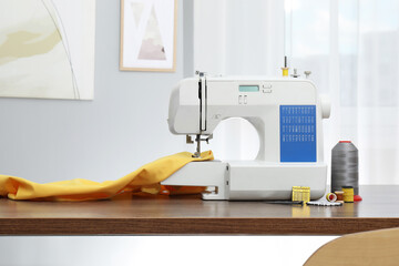 Sewing machine with fabric and craft accessories on wooden table indoors