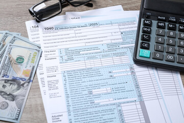 Payroll. Tax return forms, dollar banknotes, glasses and calculator on wooden table