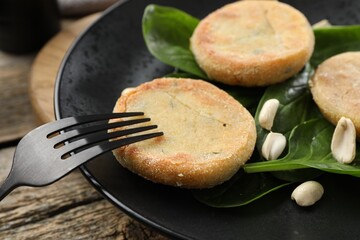 Plate with healthy dish high in vegetable fats and fork on wooden table, closeup