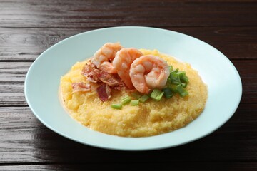 Plate with fresh tasty shrimps, bacon and grits on dark wooden table
