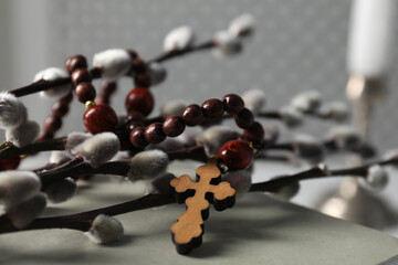 Rosary beads, willow branches and book on table, closeup