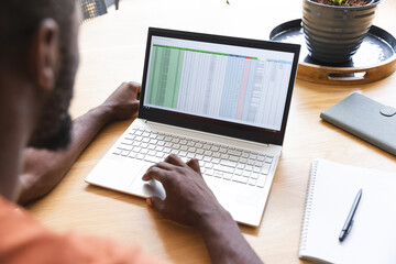 An African American male studying spreadsheet on laptop at home