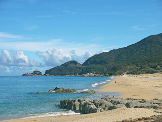 Yakushima coast panorama on sunny day, Inakahama sandy beach turquoise sea water, blue sky, distant...
