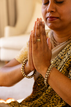 Indian woman with hands together in prayer at home, eyes closing