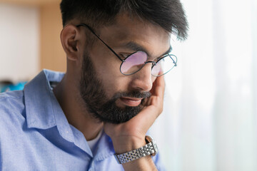 Portrait of serious business man with beard, wearing glasses looking at computer monitor while...