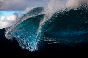Large powerful blue slab wave breaking on a shallow reef