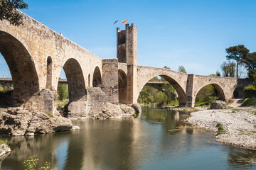 A bridge spans a river with a view of a castle in the background