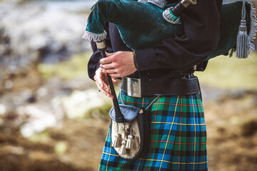 A man wearing a kilt and holding a pipe