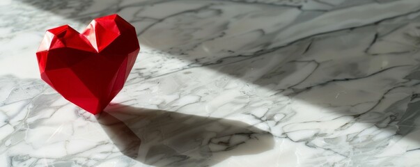 Red origami heart on marble background.