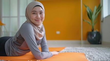 woman instructor wearing hijab t-shirt tutoring anjaneyasana yoga pose on orange pilates mattress