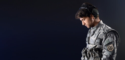 Young male soldier with tactical headset on black background