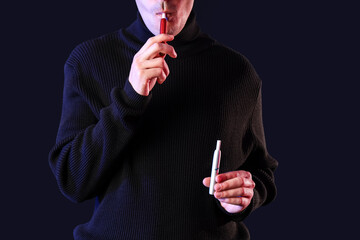 Young man smoking electronic cigarettes on black background