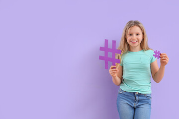 Cute teenage girl with hashtags on lilac background