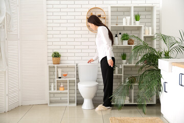 Young businesswoman flushing toilet in restroom