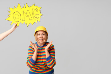 Surprised adult woman and female hand holding speech bubble with word OMG on white background