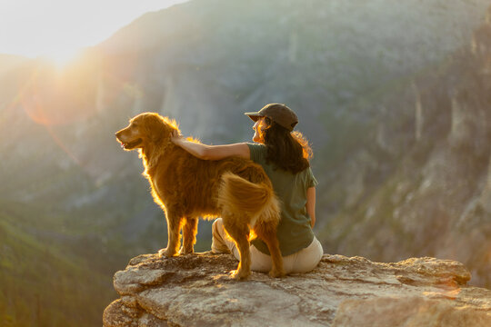 Woman and dog enjoying sunset after a hike in the summer