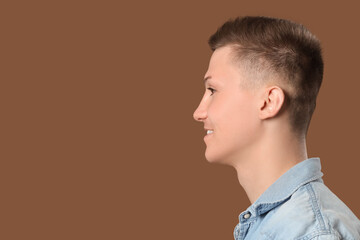 Young man with stylish haircut on brown background, closeup