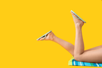 Legs of young woman in stylish flip-flops on yellow background