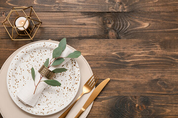Beautiful table setting with leaves and burning candle on wooden background
