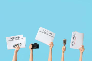 Female hands with newspapers, microphone and photo camera on color background