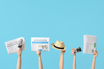 Female hands with newspapers, hat, microphone and photo camera on color background